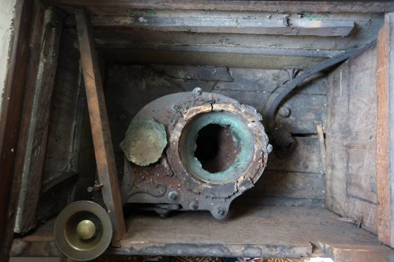 When the bowl is removed, you can see the oxidized copper pan that pulling the brass knob would tip. In the upper right, the lead pipe and wire that ran to a cistern to flush the toilet.